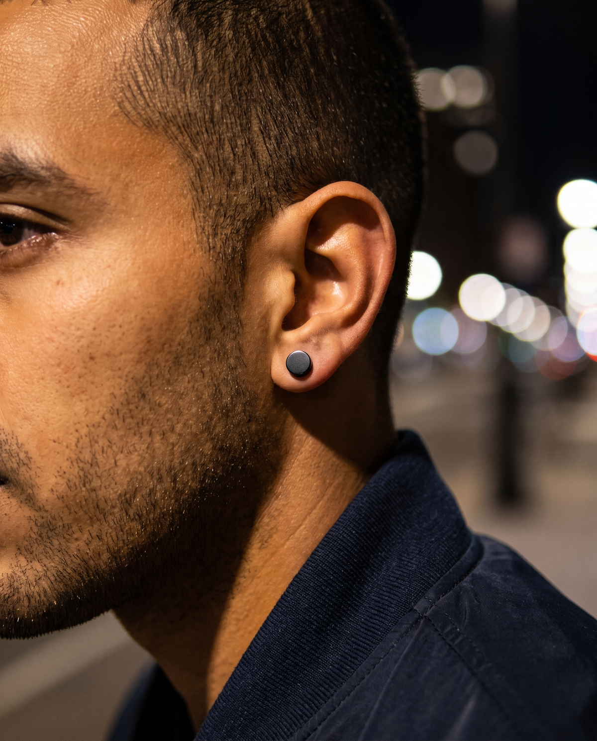 The Onyx Stud Collection worn on ear, night city bokeh